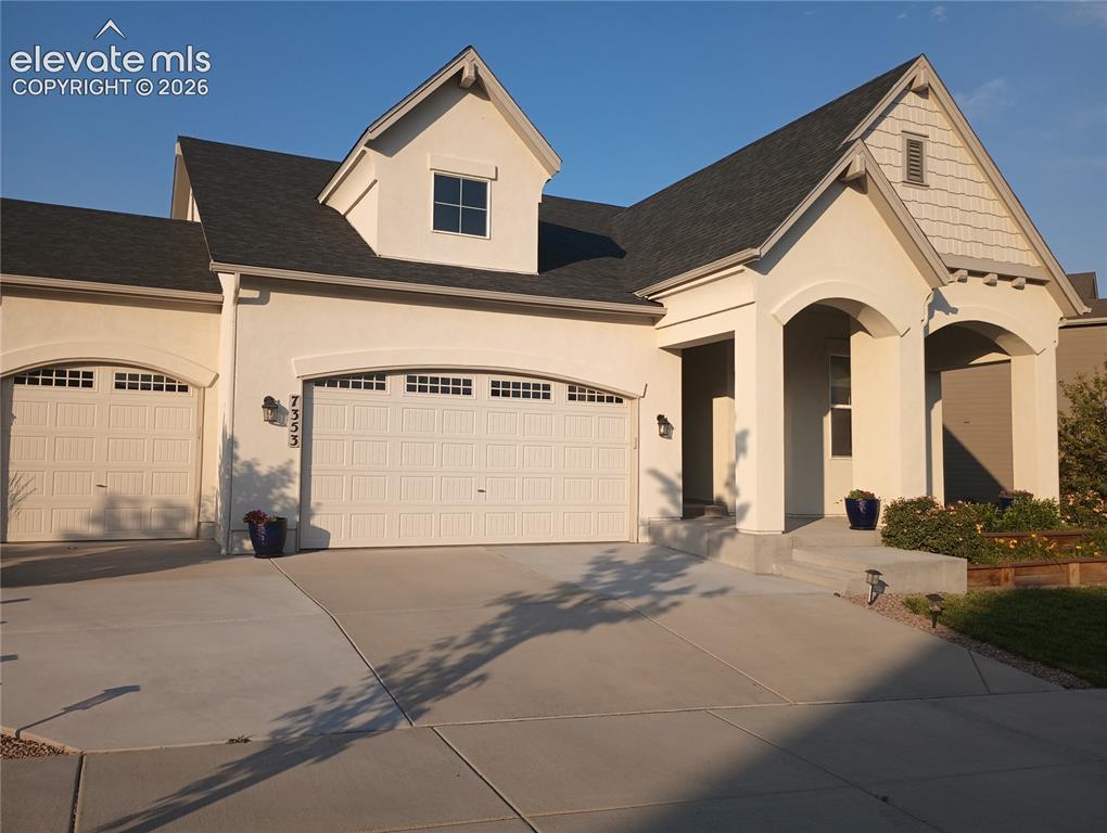Image 1 of 1: Stucco exterior with a prominent arched entry and a shingled gable accent