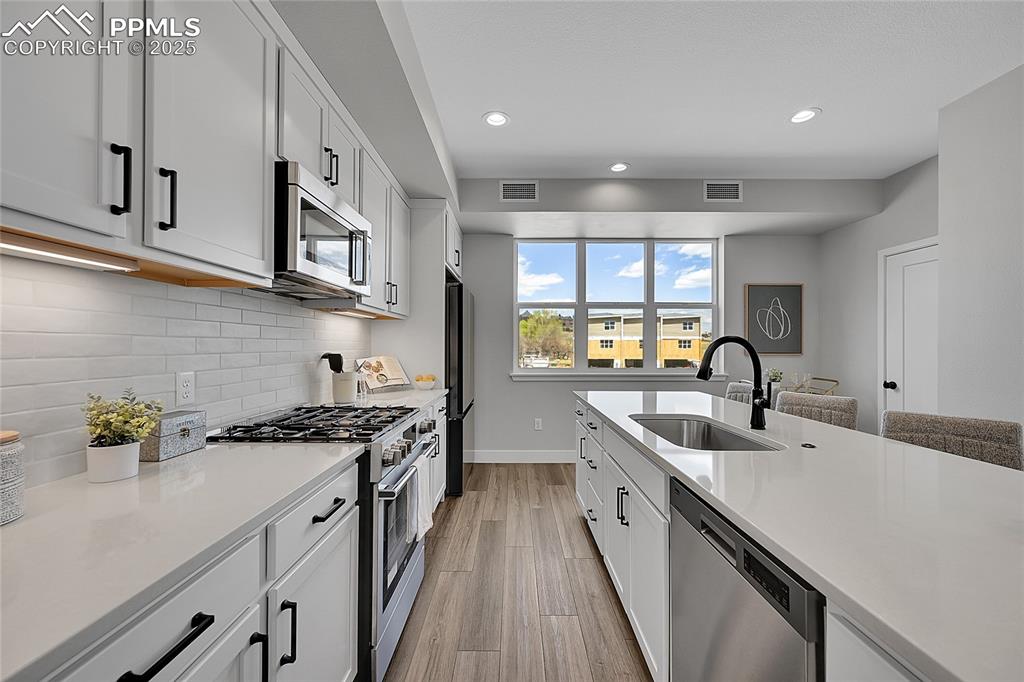 Image 10 of 31: Kitchen featuring visible vents, decorative backsplash, a sink, and stainle