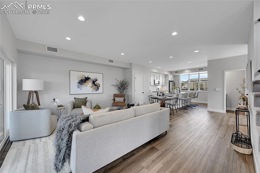 Image 19 of 31: Living area with light wood finished floors and recessed lighting