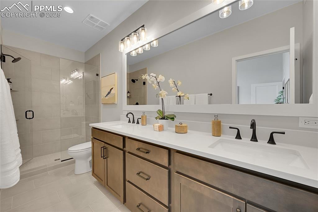 Image 26 of 31: Full bath with a stall shower, double vanity, visible vents, and a sink
