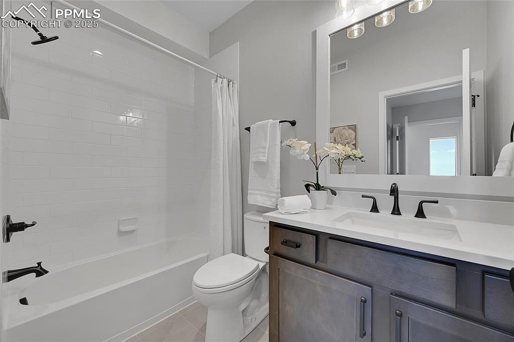 Image 28 of 31: Full bath featuring vanity, shower / tub combo with curtain, toilet, tile p