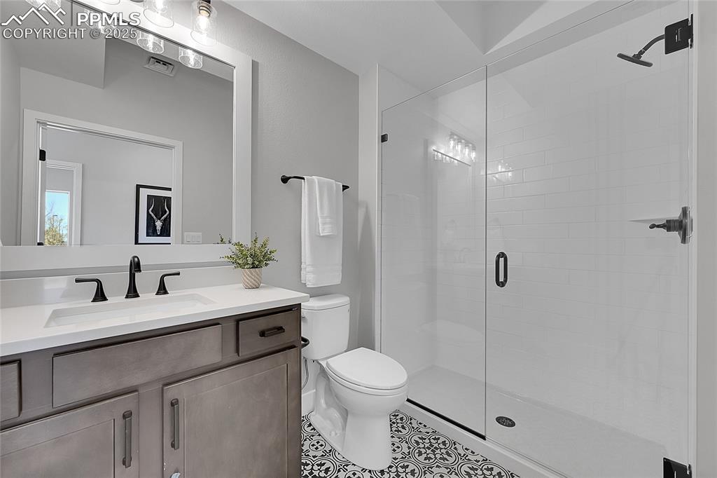 Image 7 of 31: Full bathroom with vanity, toilet, a shower stall, tile patterned floors, a