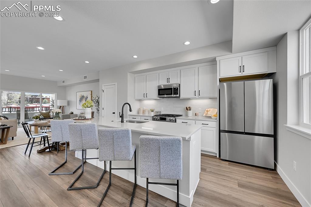 Image 9 of 31: Kitchen featuring light countertops, a sink, white cabinets, and appliances