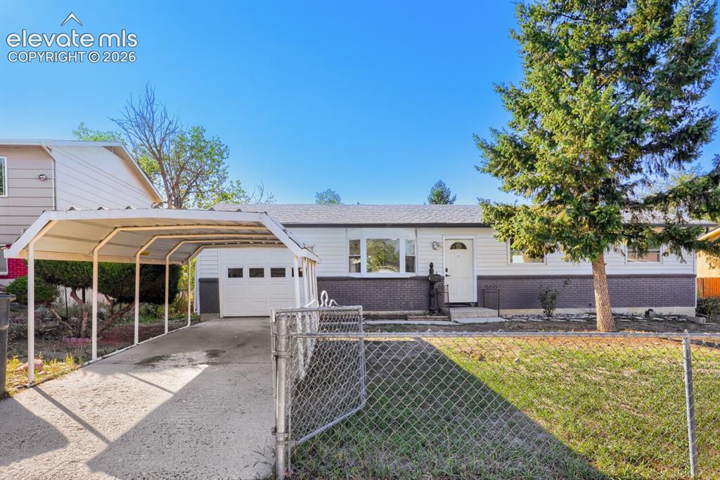 Caption: White siding exterior with a dark brick facade, an attached single-car garage, and a covered carport
