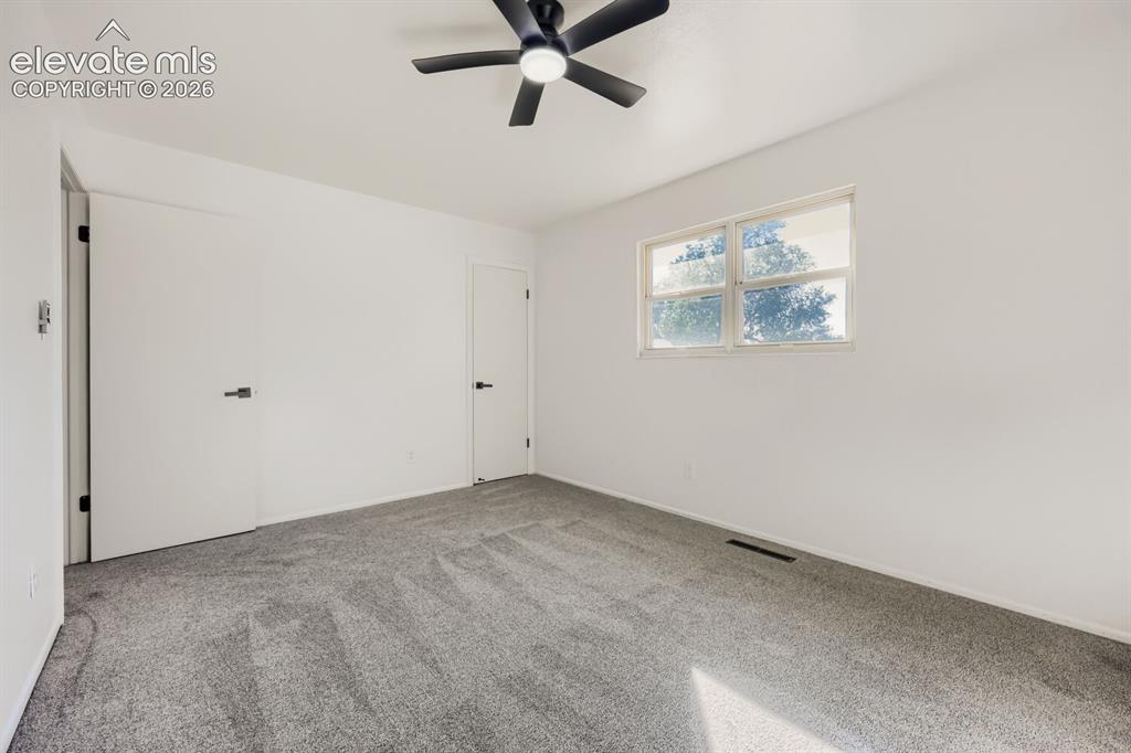 Image 12 of 22: Wall-to-wall carpeting, ceiling fan with light fixture, window with natural