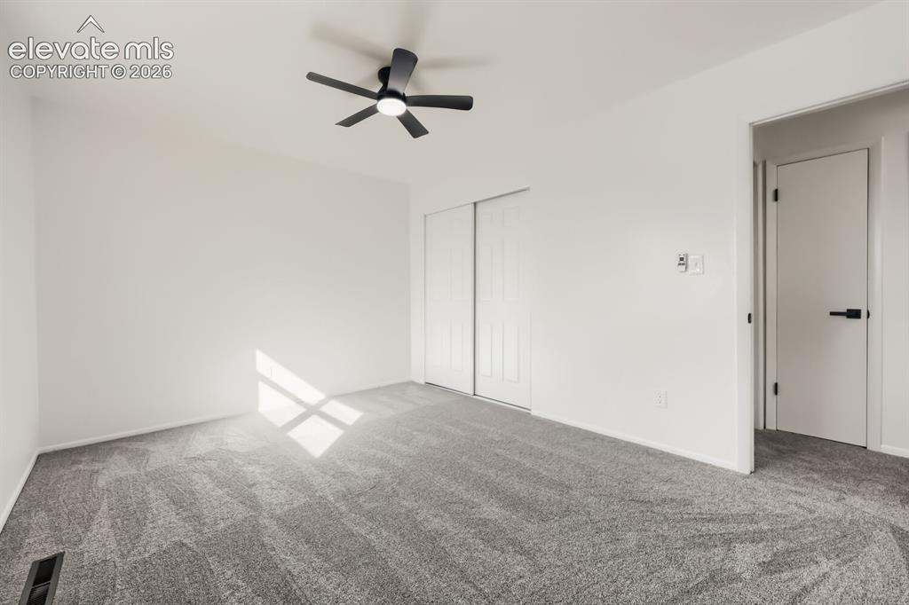 Image 13 of 22: Wall-to-wall carpeting, white walls, black ceiling fan, white sliding close