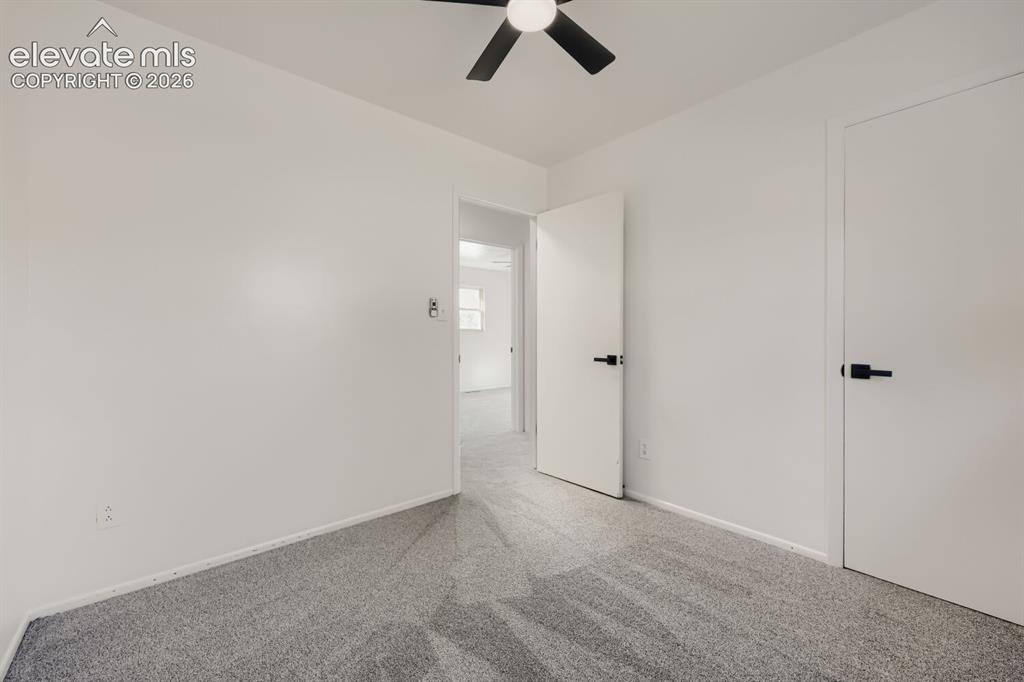 Image 15 of 22: Carpeted flooring, ceiling fan, and white doors with matte black hardware