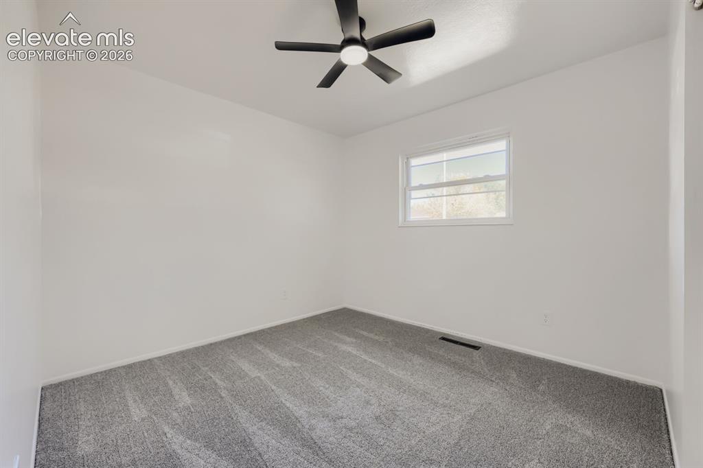 Image 16 of 22: Neutral wall paint, gray patterned carpeting, window with white trim, and a