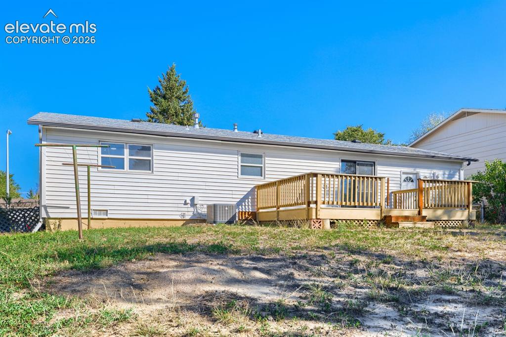 Image 21 of 22: Rear exterior with white siding, a multi-level wood deck, and a sliding gla
