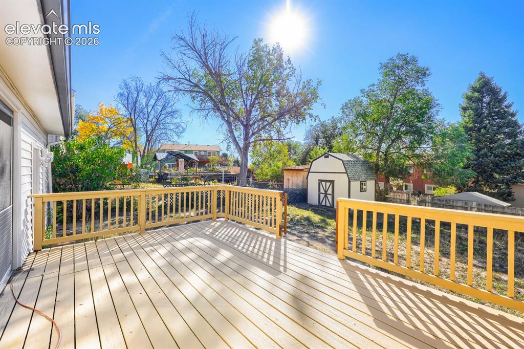 Image 22 of 22: Expansive outdoor deck with natural wood railing, white siding, and a detac