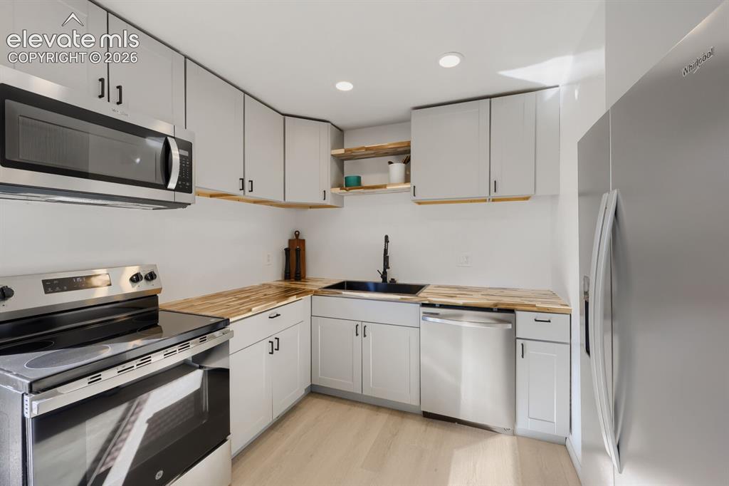 Image 8 of 22: Stainless steel appliances, light gray cabinetry, wood-finish countertops,