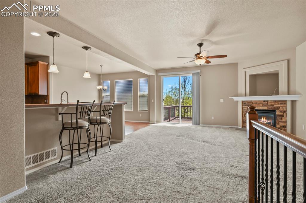 Image 5 of 42: Living room with a cozy fireplace, with the kitchen to the left