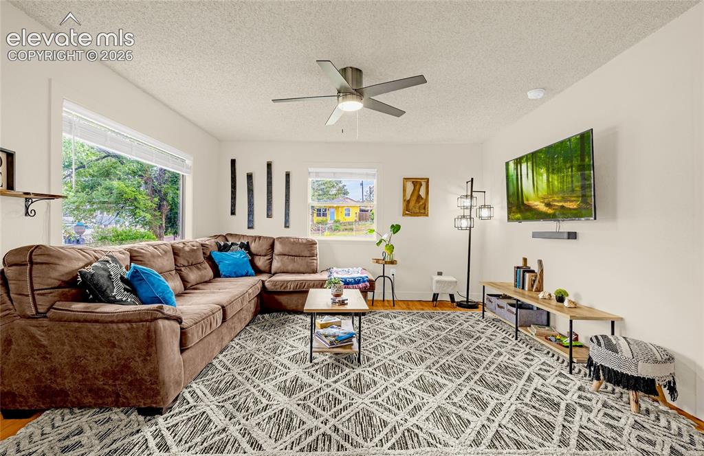 Image 16 of 46: Hardwood flooring, white walls, large windows, and a ceiling fan