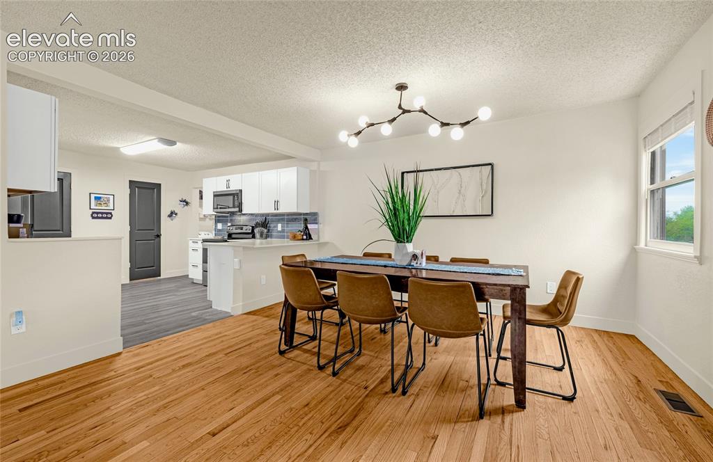 Image 17 of 46: Hardwood flooring, contemporary chandelier, kitchen pass-through, neutral w