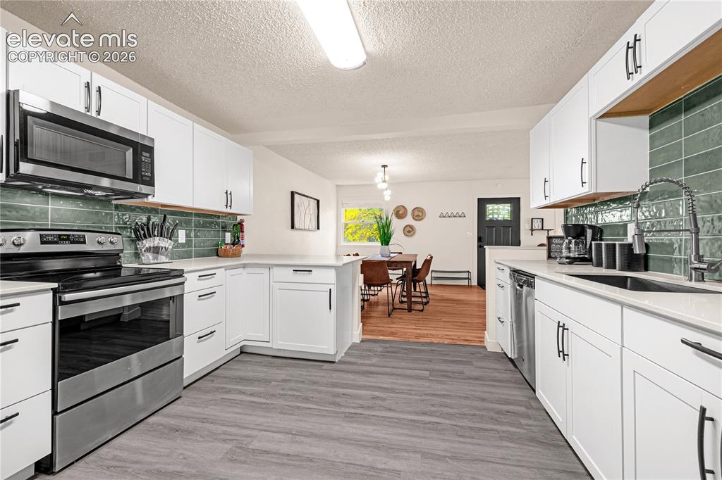 Image 22 of 46: White shaker cabinetry with dark hardware, stainless steel appliances, ligh