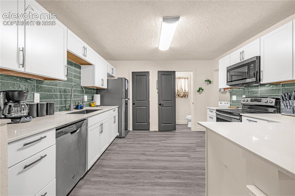 Image 23 of 46: Kitchen featuring white cabinetry, light countertops, subway tile backsplas