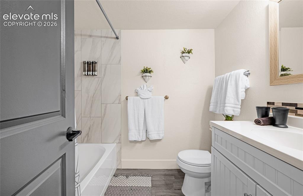 Image 31 of 46: Bathroom featuring a white bathtub with large format wall tiles, a light-to