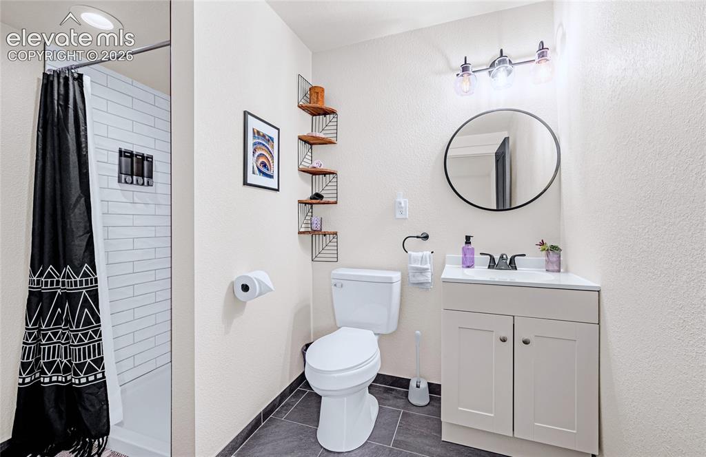 Image 33 of 46: White subway tile shower surround, recessed overhead lighting, vanity with 