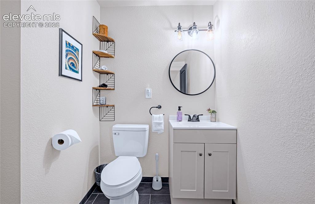 Image 34 of 46: Powder room featuring a single vanity with a white countertop, round mirror