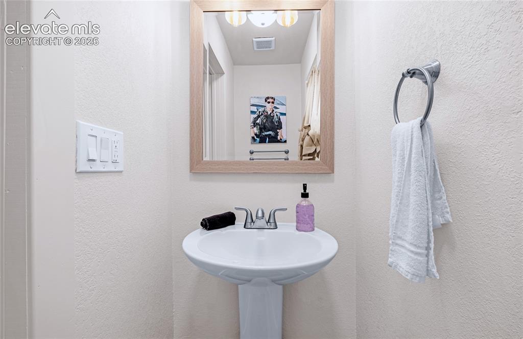 Image 35 of 46: Pedestal sink with chrome faucet, framed mirror, and wall-mounted towel rin