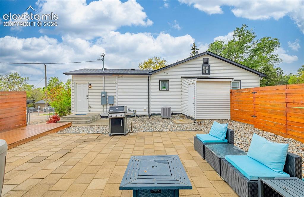 Image 39 of 46: Spacious outdoor living area with paver patio, wood deck, and wood privacy 