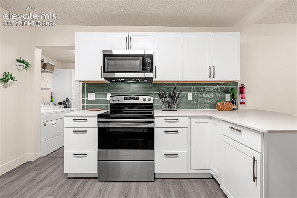 Image 8 of 46: White flat-panel cabinetry, stainless steel appliances, light-toned counter
