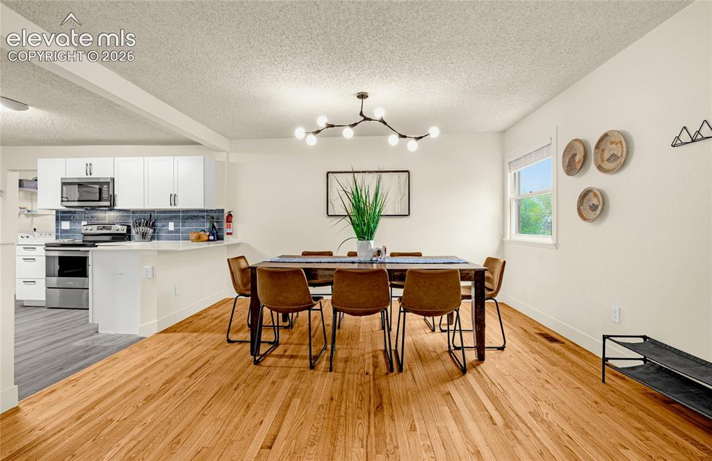 Image 9 of 46: Hardwood flooring throughout the dining area, modern chandelier lighting, a