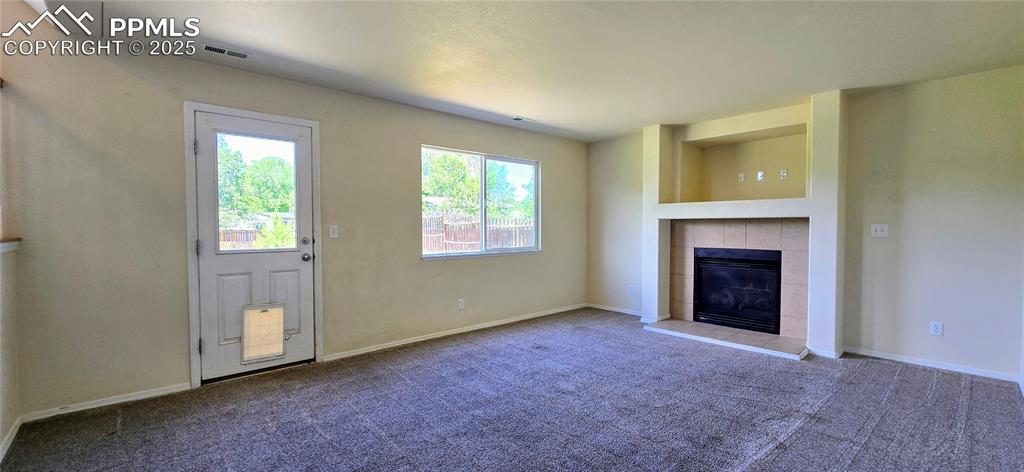 Image 2 of 24: Unfurnished living room with a tile fireplace and carpet