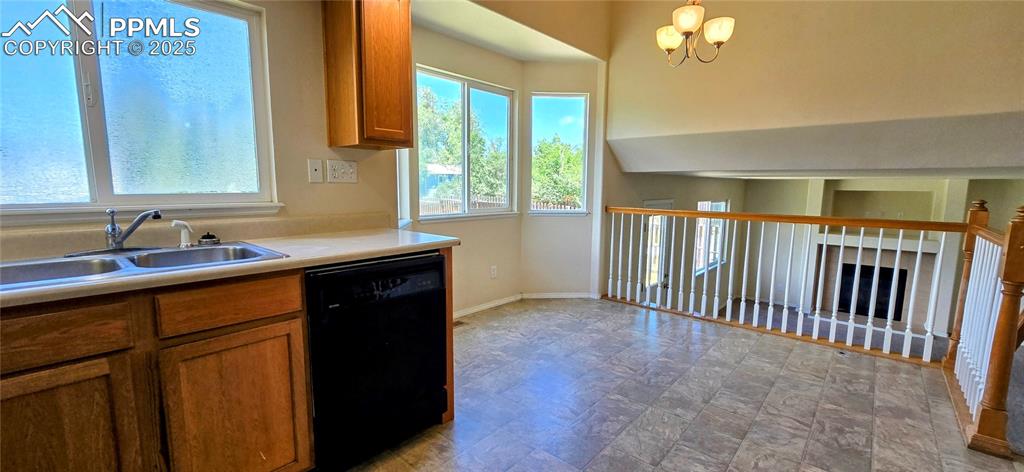 Image 3 of 24: Kitchen with black dishwasher, brown cabinets, a chandelier, and light coun