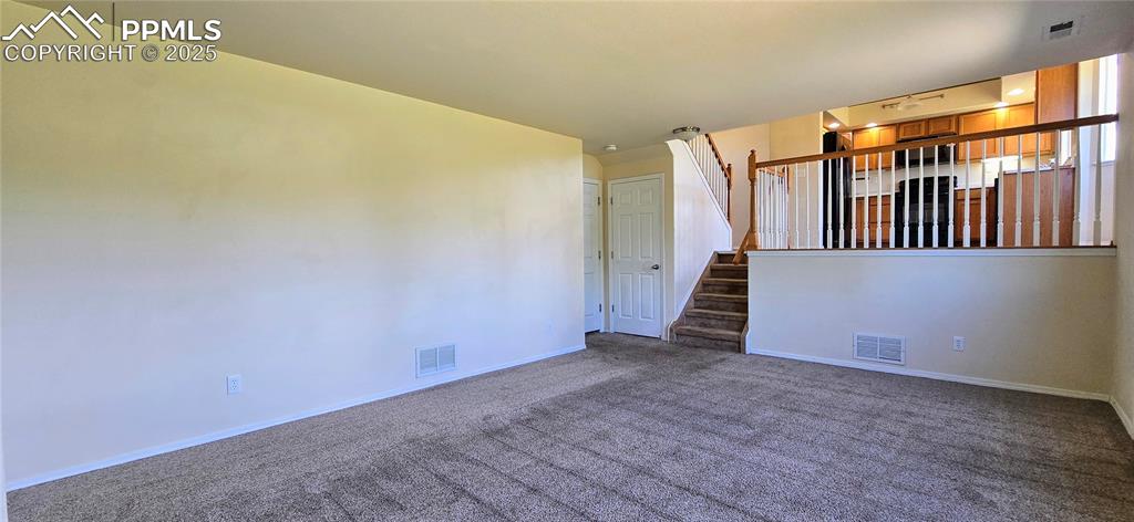 Image 7 of 24: Carpeted spare room with baseboards and stairway