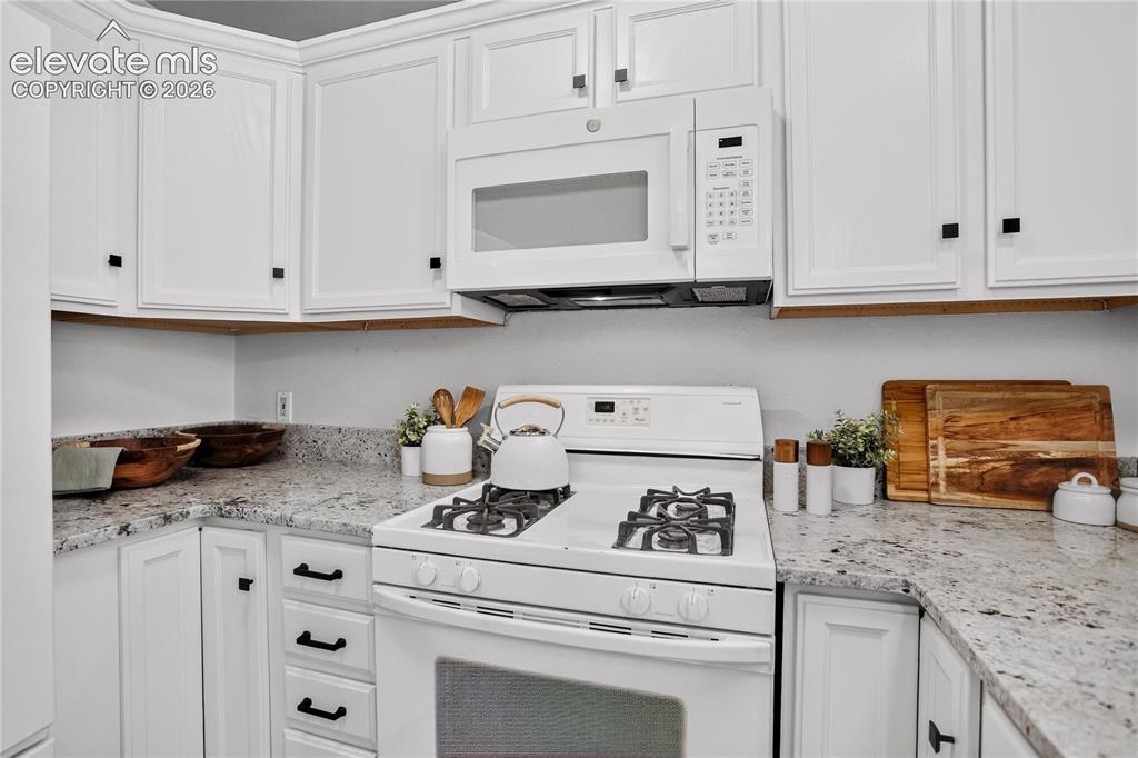 Image 12 of 35: Kitchen has granite countertops and a four burner gas range.
