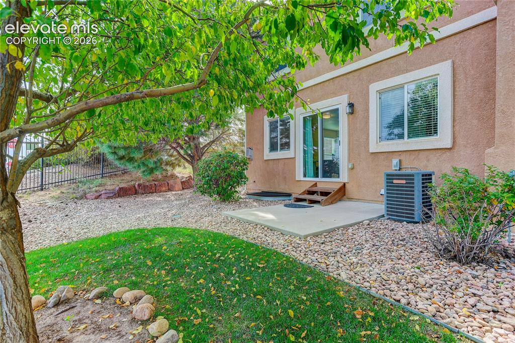 Image 31 of 35: Back patio and back yard with kidney shaped grass area.