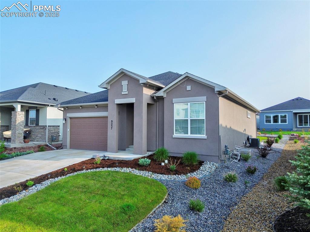 Caption: View of front of property featuring stucco siding, driveway, an attached garage, and a front yard