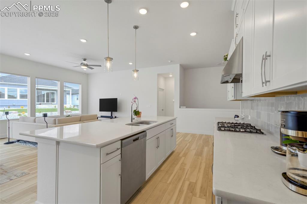 Image 21 of 45: Kitchen with white cabinetry, decorative light fixtures, open floor plan, a