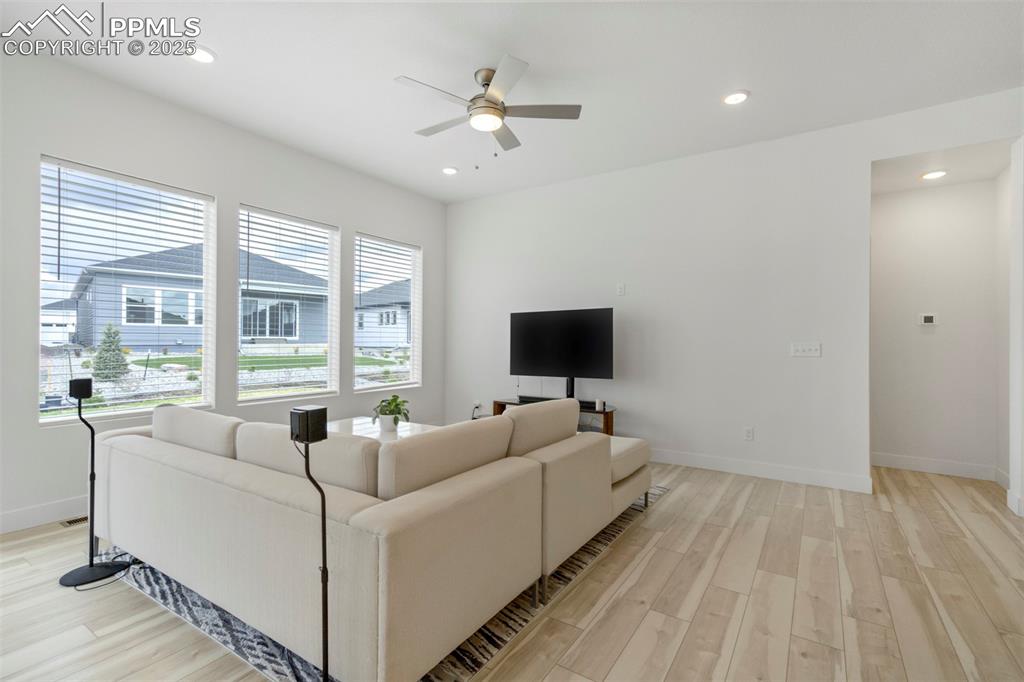 Image 25 of 45: Living area featuring light wood finished floors, ceiling fan, and recessed