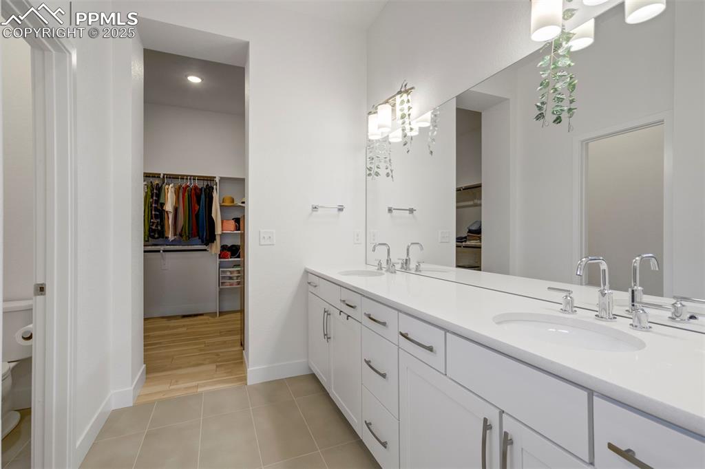 Image 29 of 45: Full bathroom with a walk in closet, double vanity, and light tile patterne