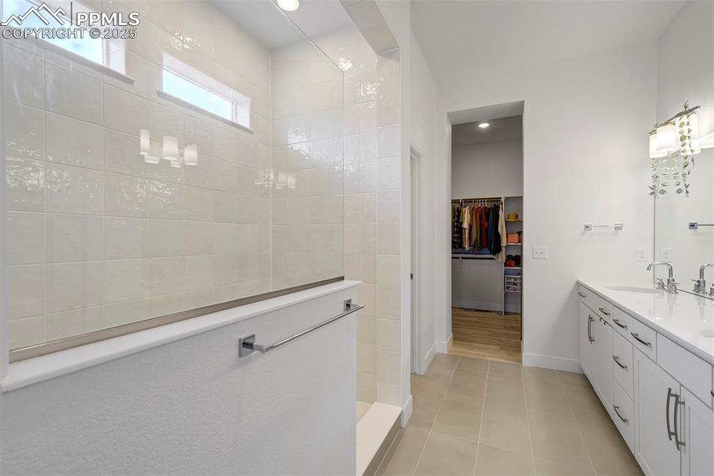 Image 30 of 45: Bathroom featuring walk in shower, double vanity, a spacious closet, light 