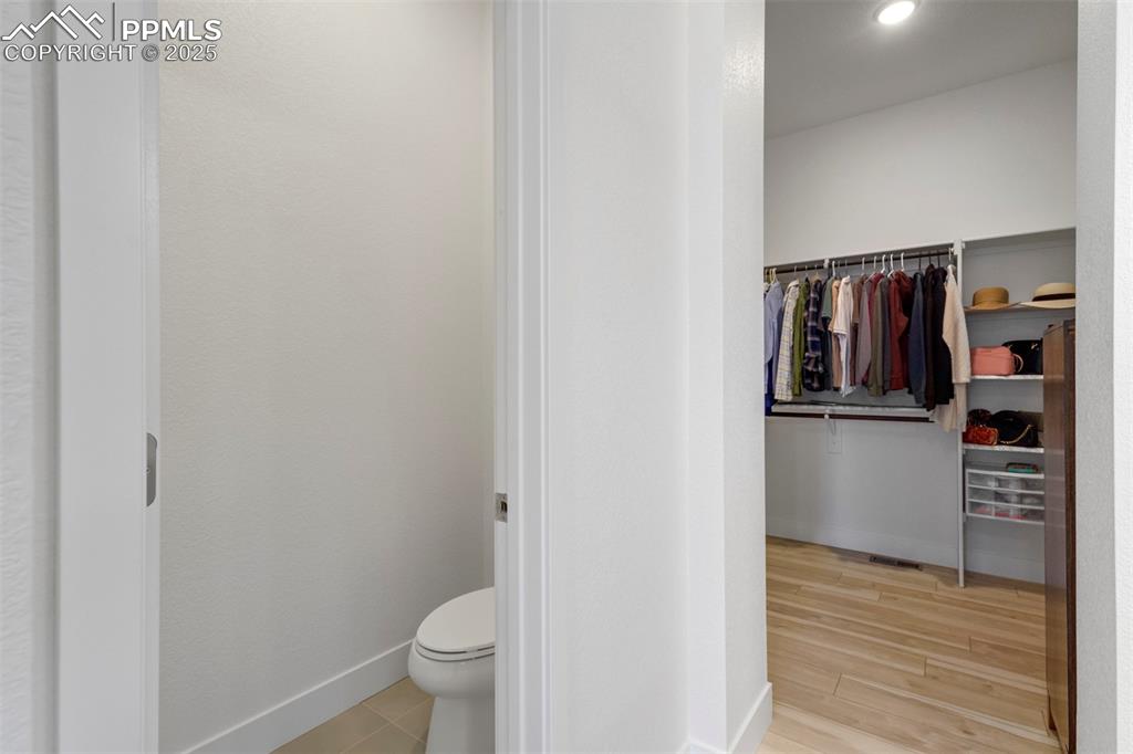 Image 32 of 45: Bathroom with a spacious closet, light wood finished floors, and recessed l