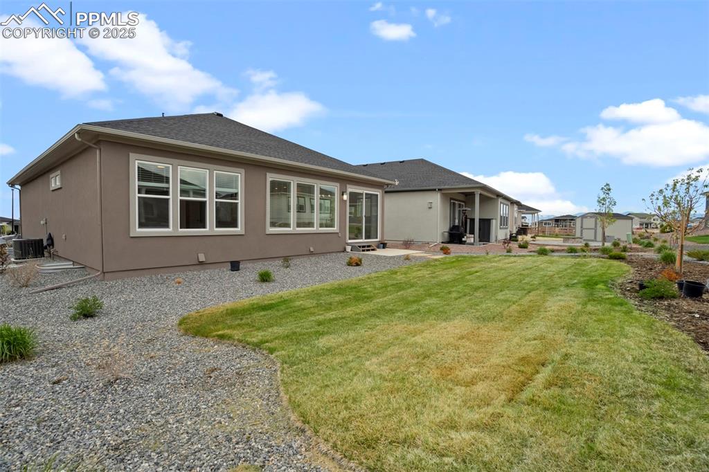 Image 44 of 45: Rear view of house with a patio area, a lawn, stucco siding, and a shingled