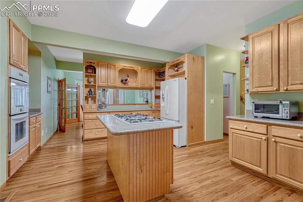 Image 19 of 50: Kitchen with open shelves, white appliances, light wood finished floors, a
