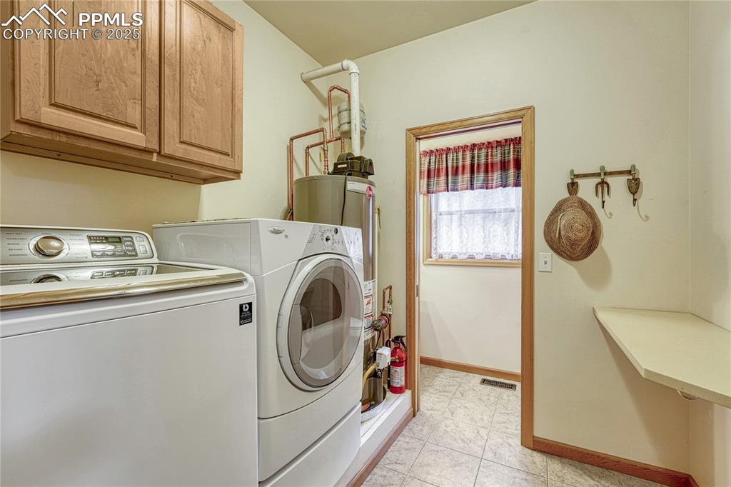 Image 23 of 50: Laundry area with cabinet space, washer and clothes dryer, and baseboards