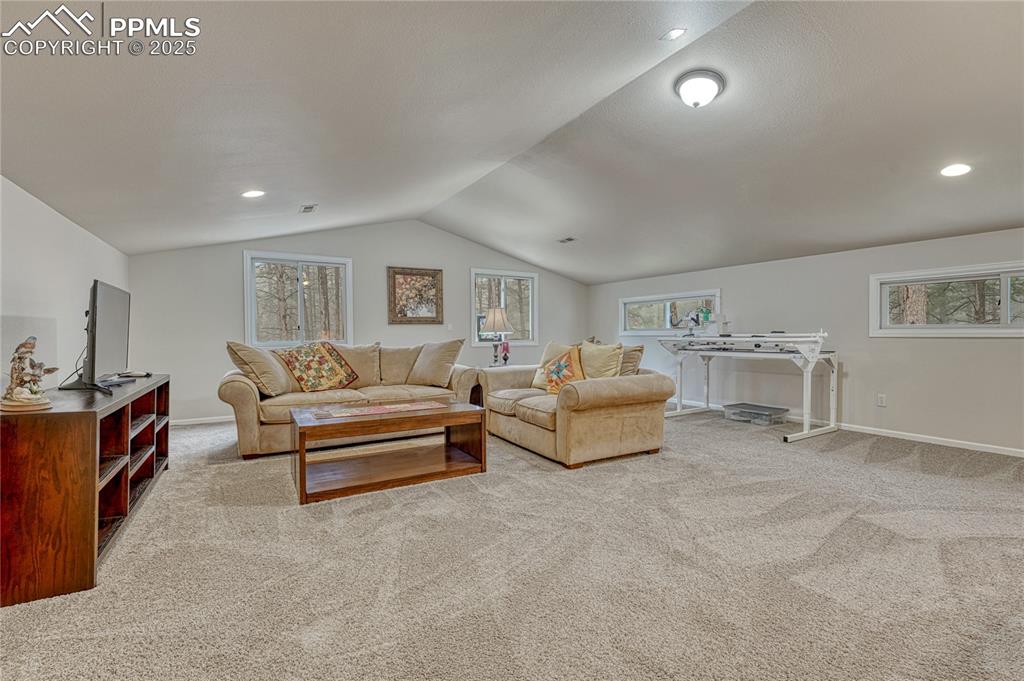Image 31 of 50: Carpeted living room featuring lofted ceiling, baseboards, and recessed lig