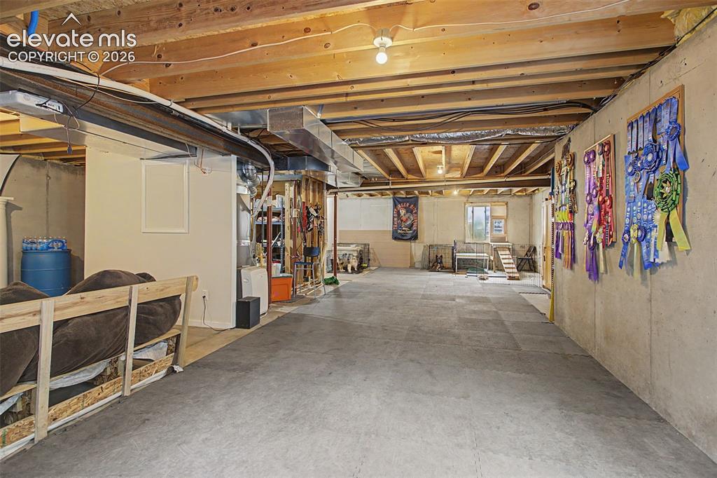 Image 32 of 45: Unfinished basement featuring exposed wood ceiling joists, concrete floorin