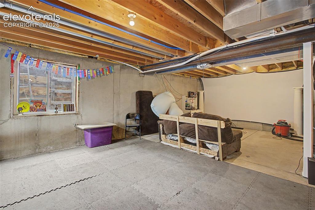 Image 34 of 45: Concrete floor basement with exposed wood joist ceiling and a single window