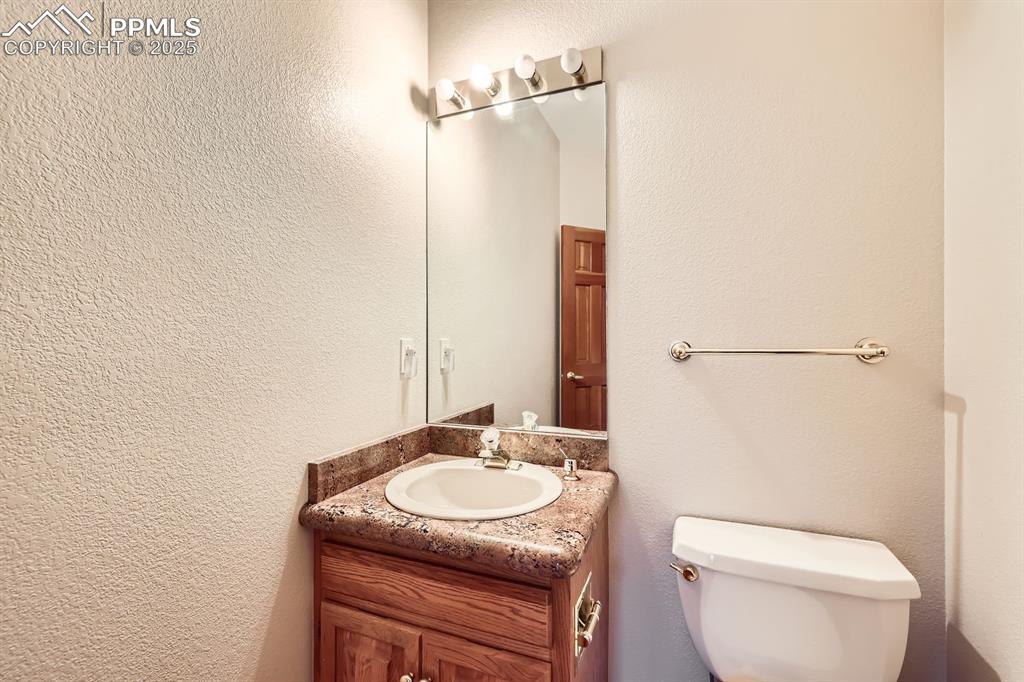 Image 13 of 31: Bathroom featuring toilet, vanity, and a textured wall