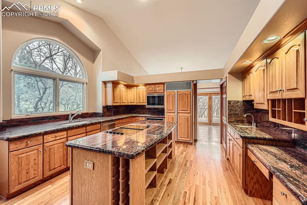 Image 7 of 31: Kitchen featuring dark stone counters, a sink, open shelves, black applianc