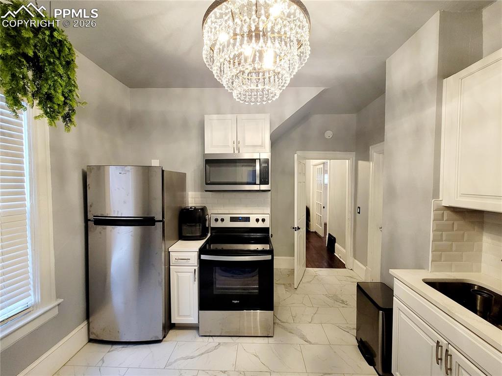 Image 10 of 21: Kitchen featuring white cabinetry, stainless steel appliances, white subway