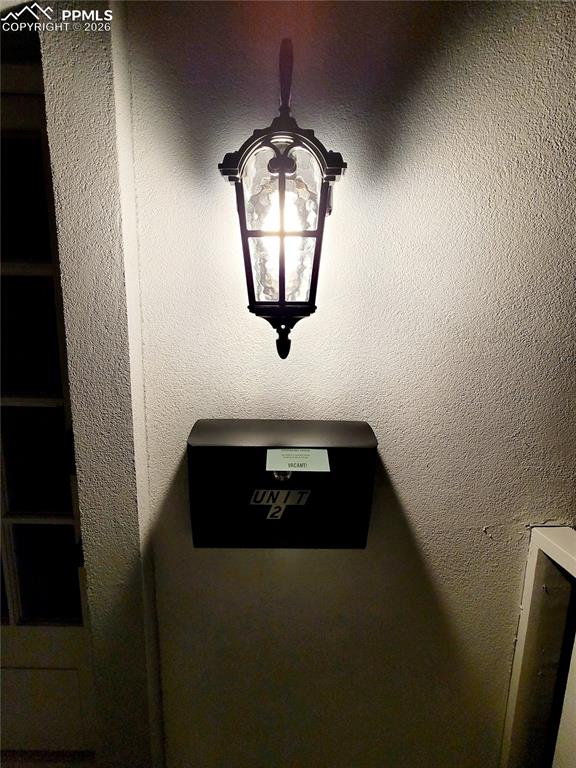 Image 13 of 21: Architectural wall lantern with clear glass panels illuminating a textured 