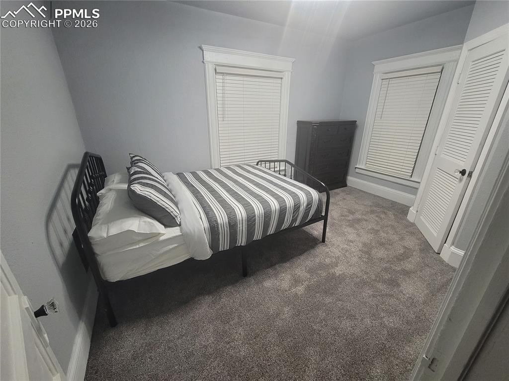 Image 16 of 21: Carpeted bedroom featuring two windows with white blinds, white trim, and a
