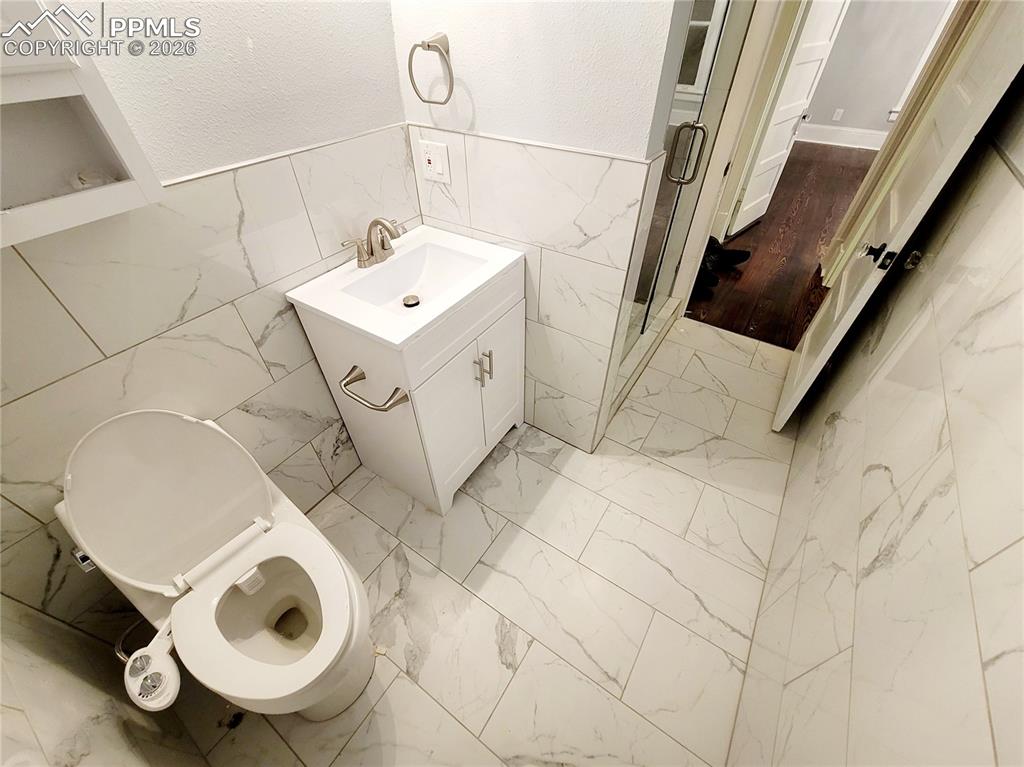 Image 20 of 21: Contemporary bathroom featuring white-veined tile flooring and wainscoting